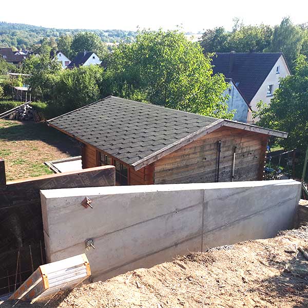 Betonstützwand über 25 Meter Länge zum Hang abfangen - Erdaushub und Armierung der untersten Ebene.